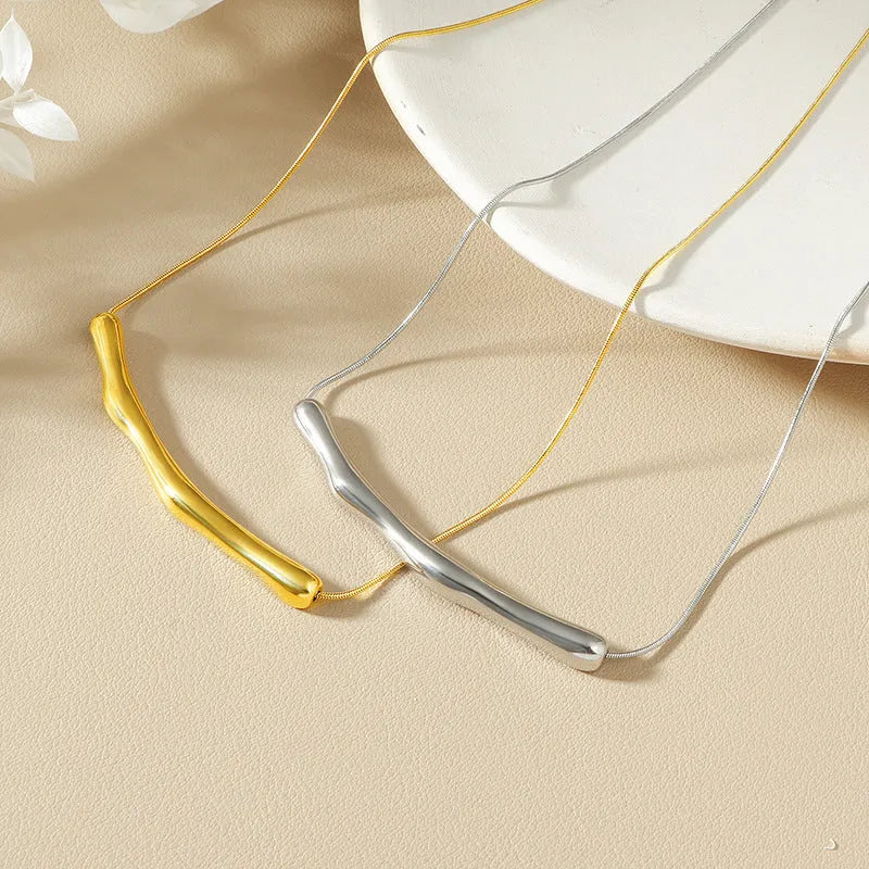 Close-up of a women's titanium steel necklace with an irregular pleated textured pendant in a gold tone.