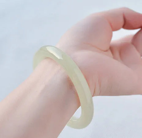 Ice-like silk jade round bar bracelet showing geometric winding design on a wrist.