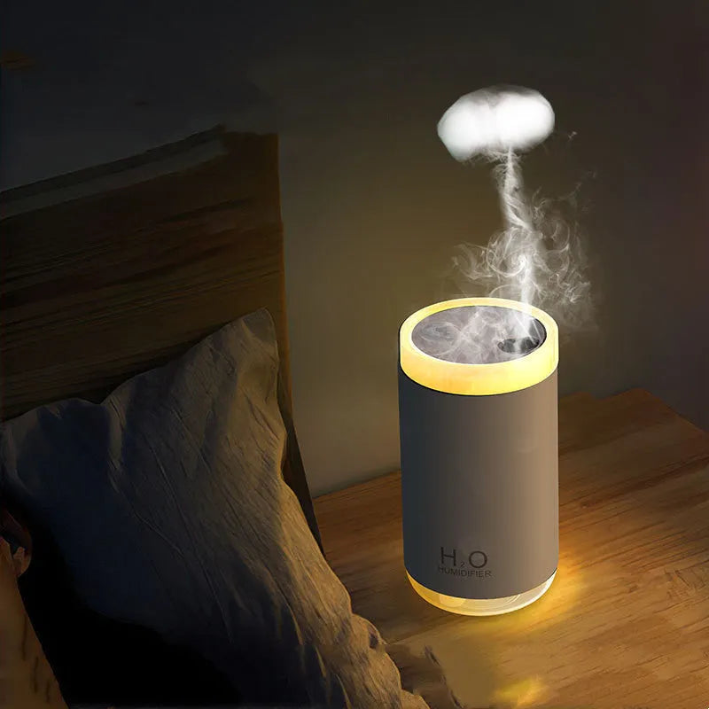 White USB jellyfish smoke ring humidifier with warm night light on a table, showing nano mist.