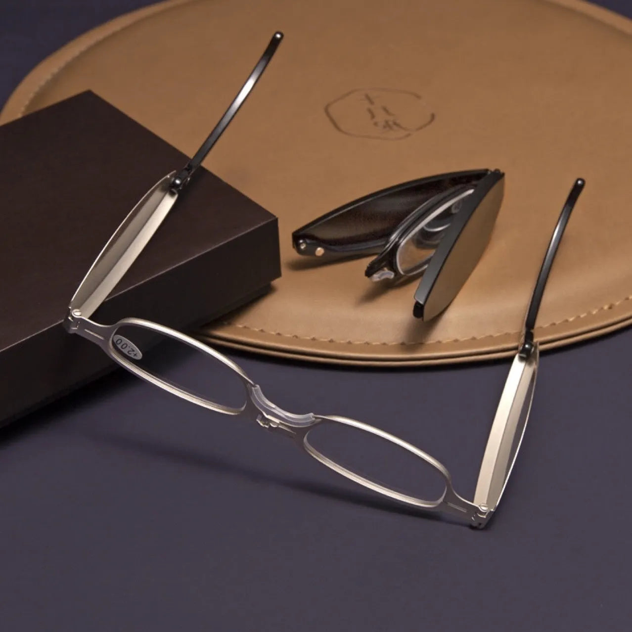 Black folding presbyopic glasses with metal frame and ring detailing shown open and folded