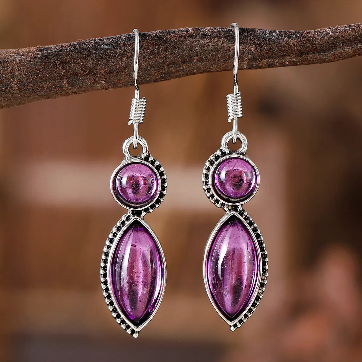 A pair of vintage geometric drop earrings with a round gemstone, in black and purple electroplated zinc alloy.