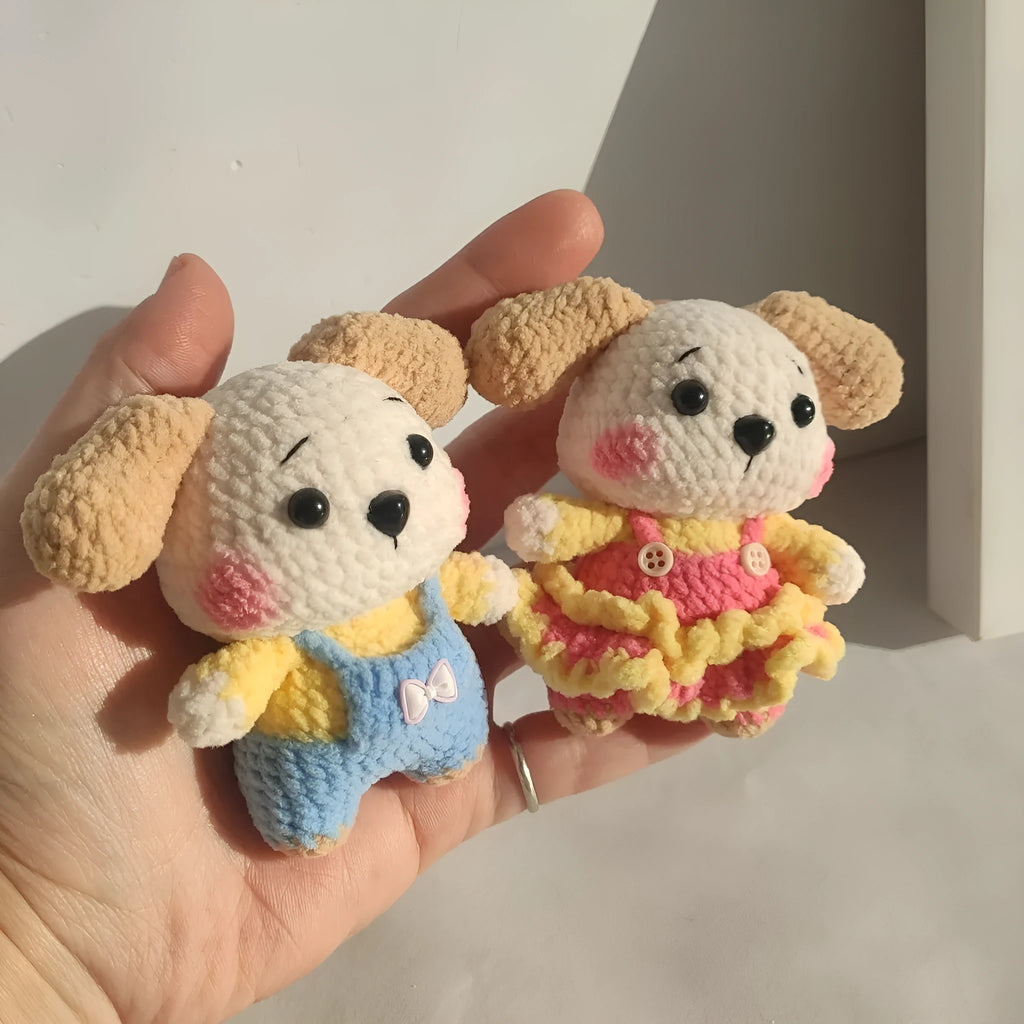 A pair of wool zodiac dog pendant charms on keychains, one wearing a strap skirt and the other strap pants.