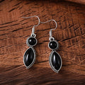 A pair of vintage geometric drop earrings with a round gemstone, in black and purple electroplated zinc alloy.