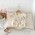 Apricot cotton baby romper with embroidered sunflower, short sleeves, triangle jumpsuit shape and hidden hook closure.