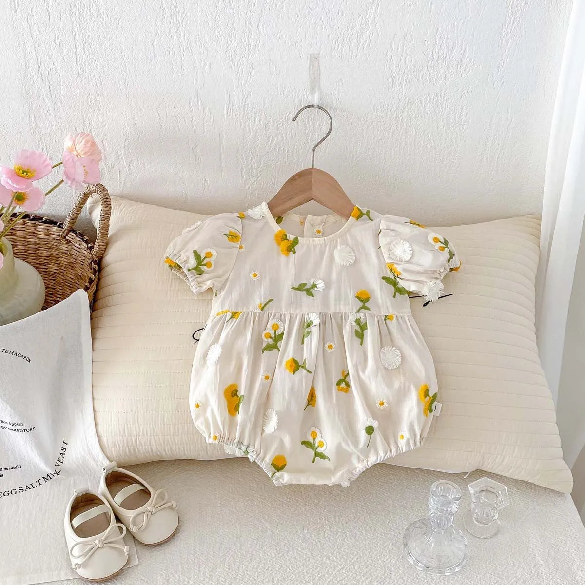 Apricot cotton baby romper with embroidered sunflower, short sleeves, triangle jumpsuit shape and hidden hook closure.