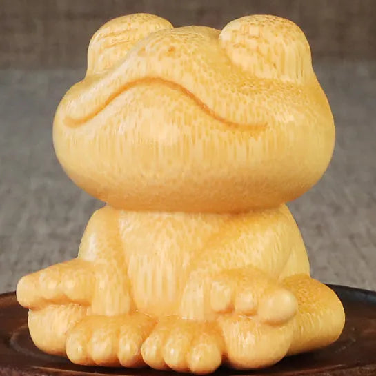 Small smiling frog ornament carved from solid bamboo on a plain background.