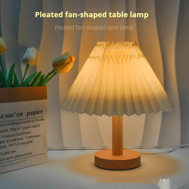 Vintage red pleated umbrella-shaped bedside lamp with remote control on a wooden nightstand.