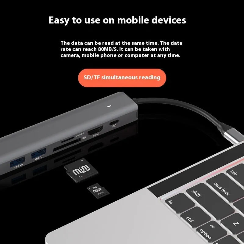 Silver aluminium 7-in-1 USB hub with SD card slot, microSD slot, USB-C PD port, and multiple USB-A ports.