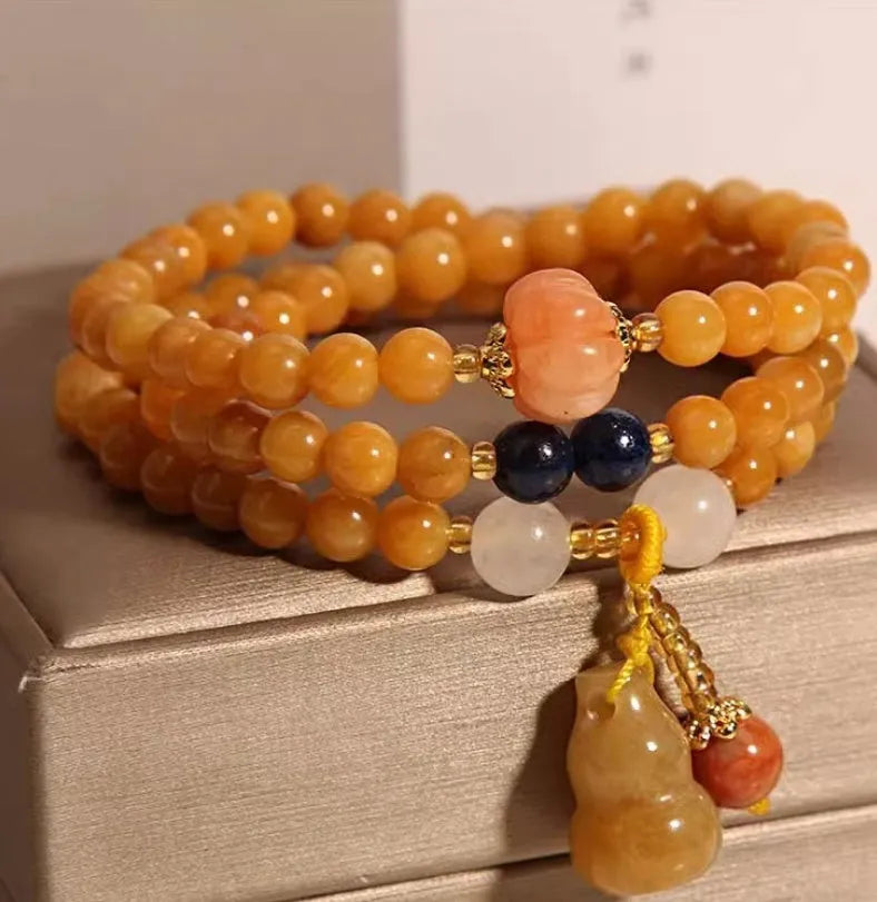 Women's multi-circle bracelet with three strands of natural Jinsi Jade beads and a resin flower calabash pendant on a white background