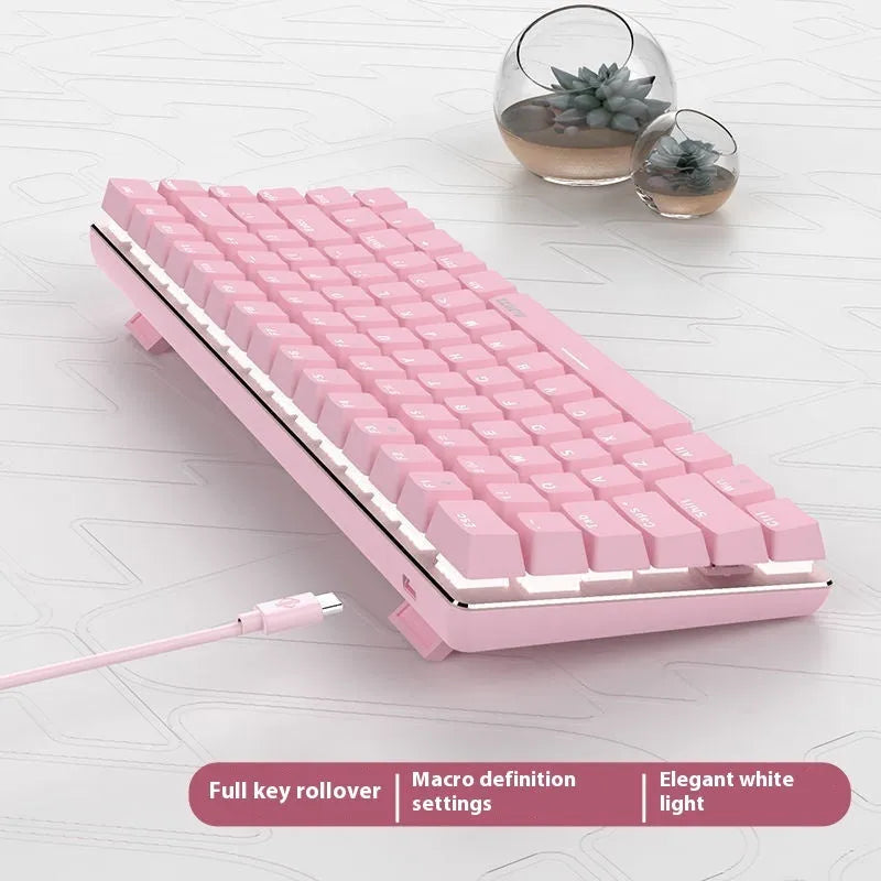 Compact white-backlit mechanical keyboard with 82 keys and metal body next to a laptop.