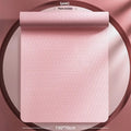 Monet pink TPE fitness mat with printed guide lines, shown rolled and unrolled on a floor.