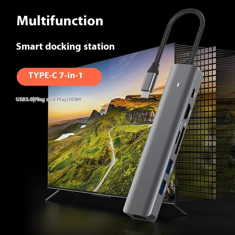 Silver aluminium 7-in-1 USB hub with SD card slot, microSD slot, USB-C PD port, and multiple USB-A ports.