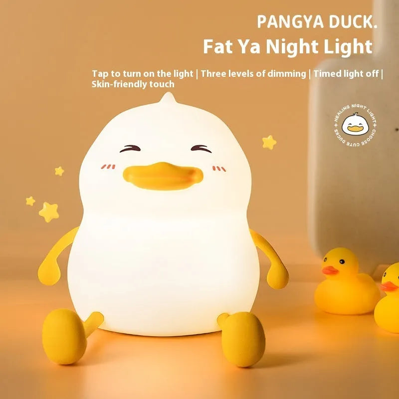 Chubby silicone pat night light on a desk showing soft LED glow and USB charging cable.