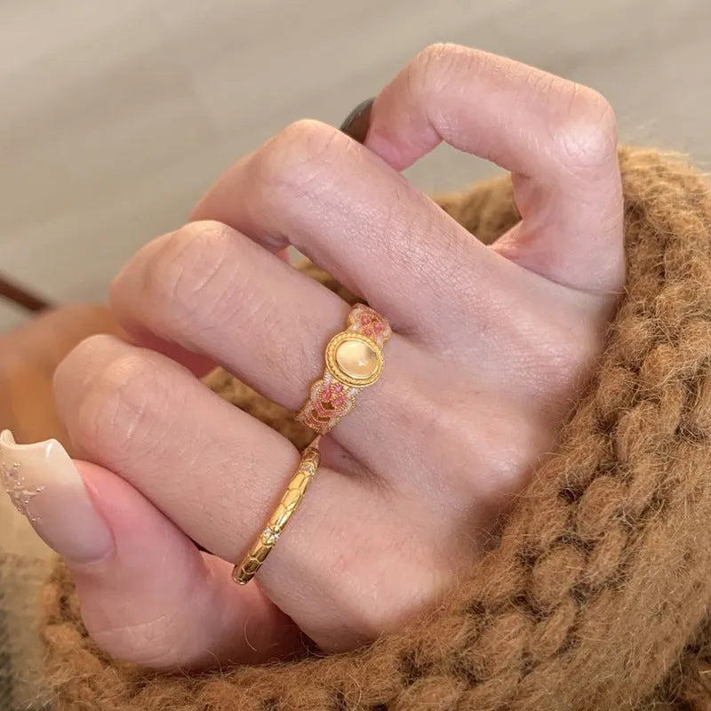 Gold geometric open ring with a pink crystal enamel stone on a model's finger.
