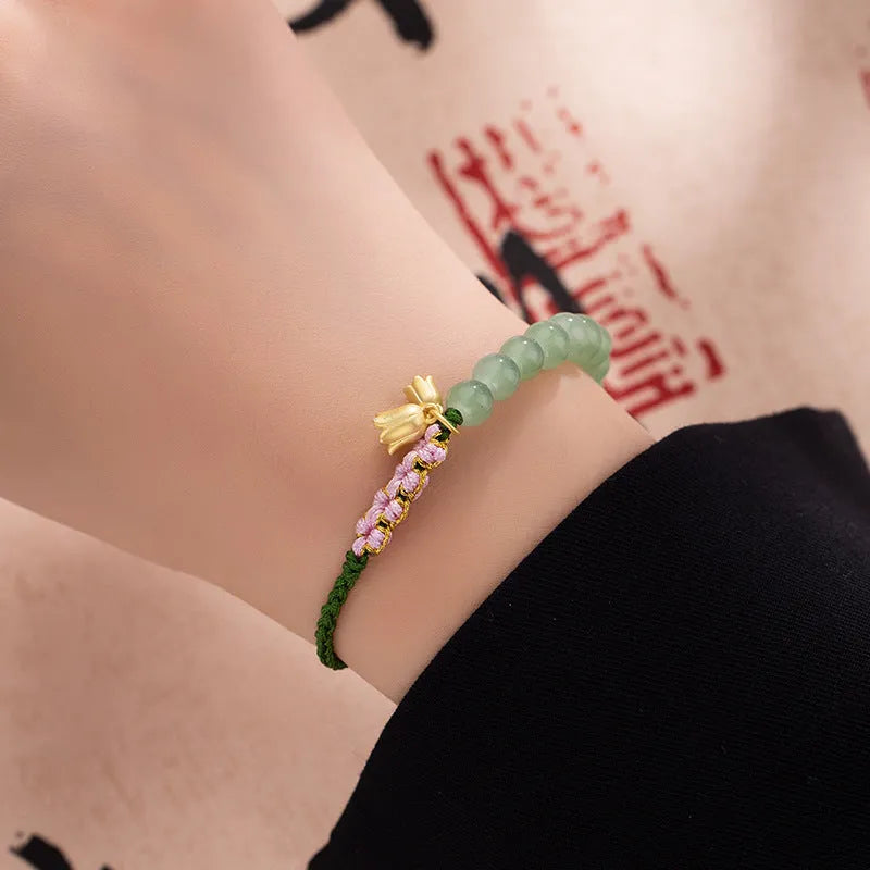 Close-up of a hand-woven red rope bracelet with floral design details on a wrist.
