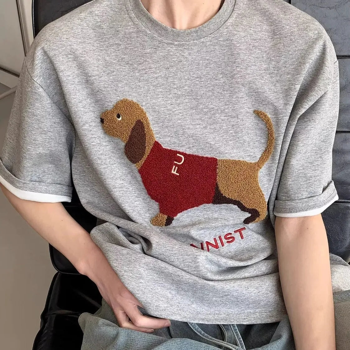 Men's grey cotton T-shirt with an embroidered sausage dog on the chest, showing short sleeves and a round neck.