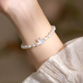 White shell pearl elastic bracelet with 925 silver rabbit charm on wrist showing rice-shaped beads and adjustable closure