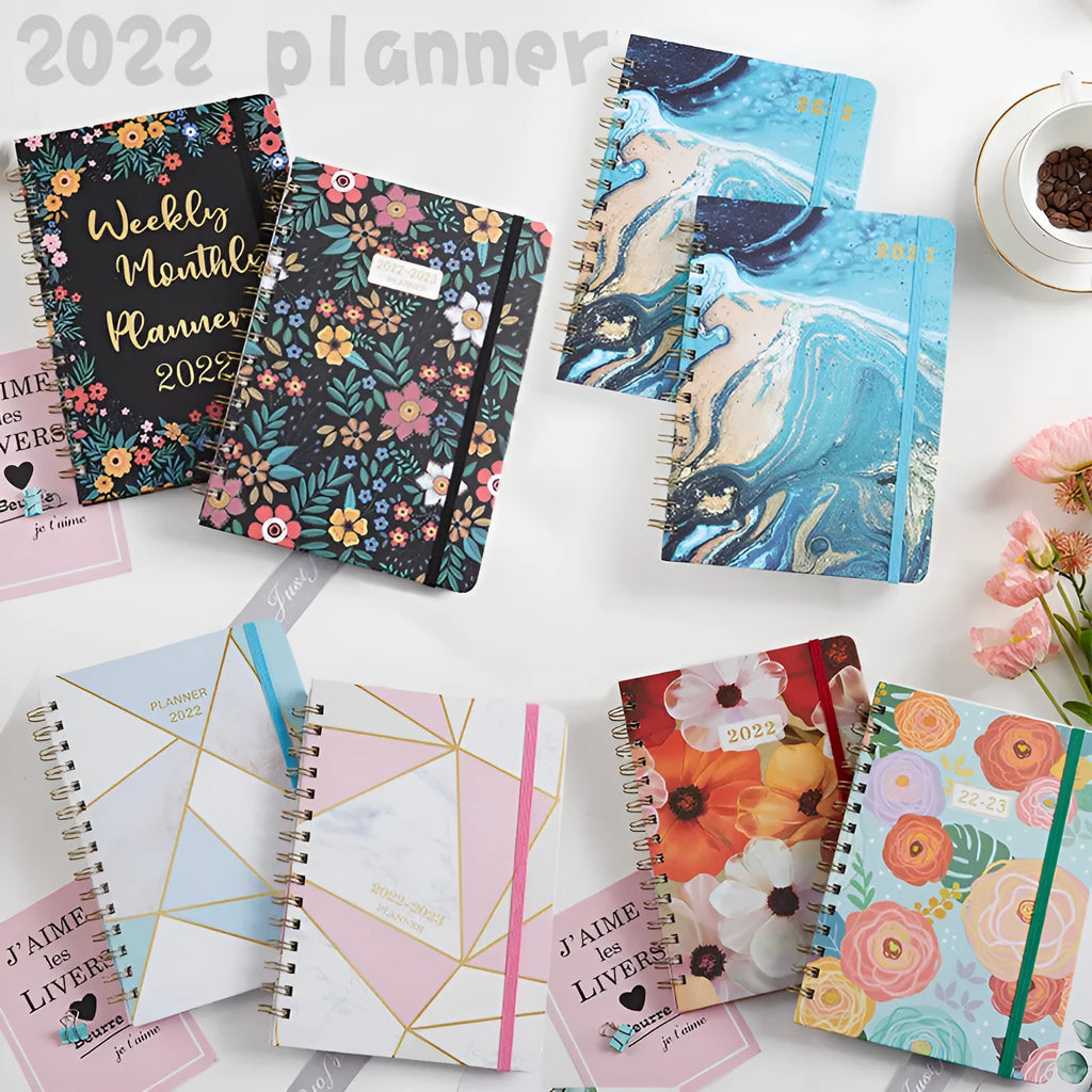 A5 spiral notebook open on a desk showing one of ten available artistic cover designs.