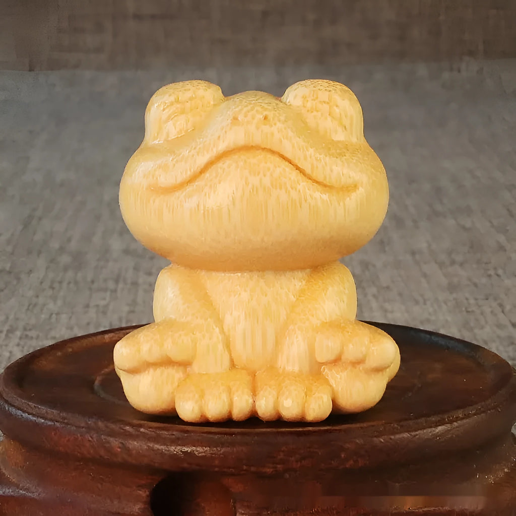 Small smiling frog ornament carved from solid bamboo on a plain background.
