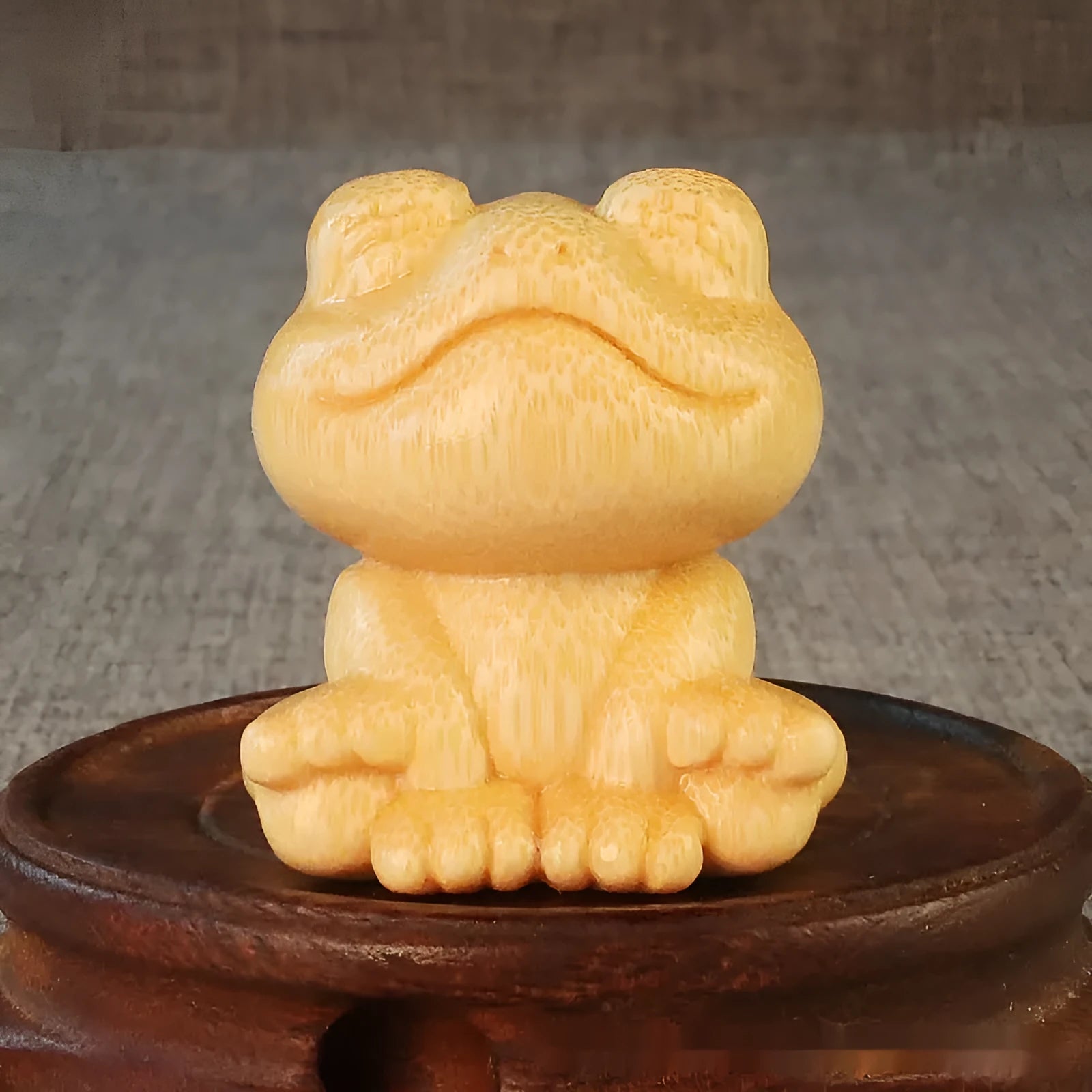 Small smiling frog ornament carved from solid bamboo on a plain background.