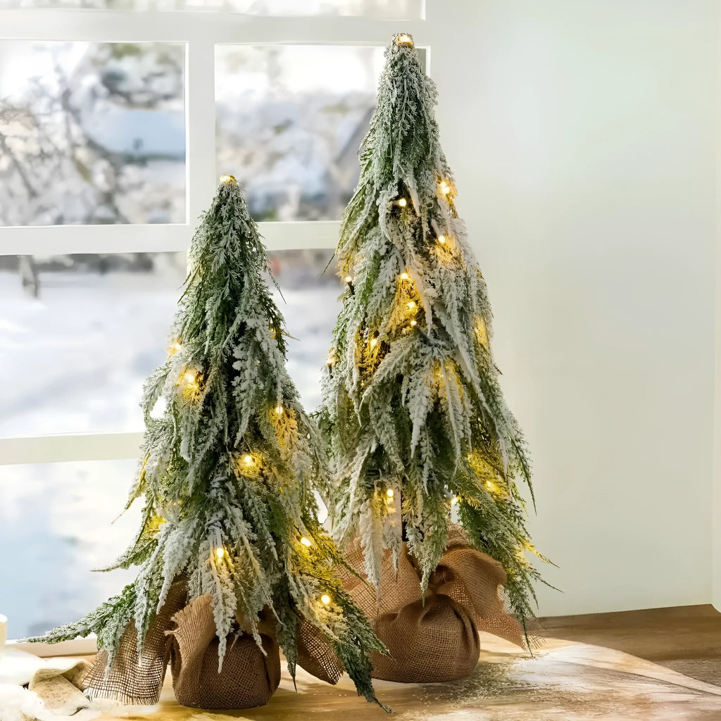 Small 24-inch artificial Christmas tree with lights and snow finish on desktop