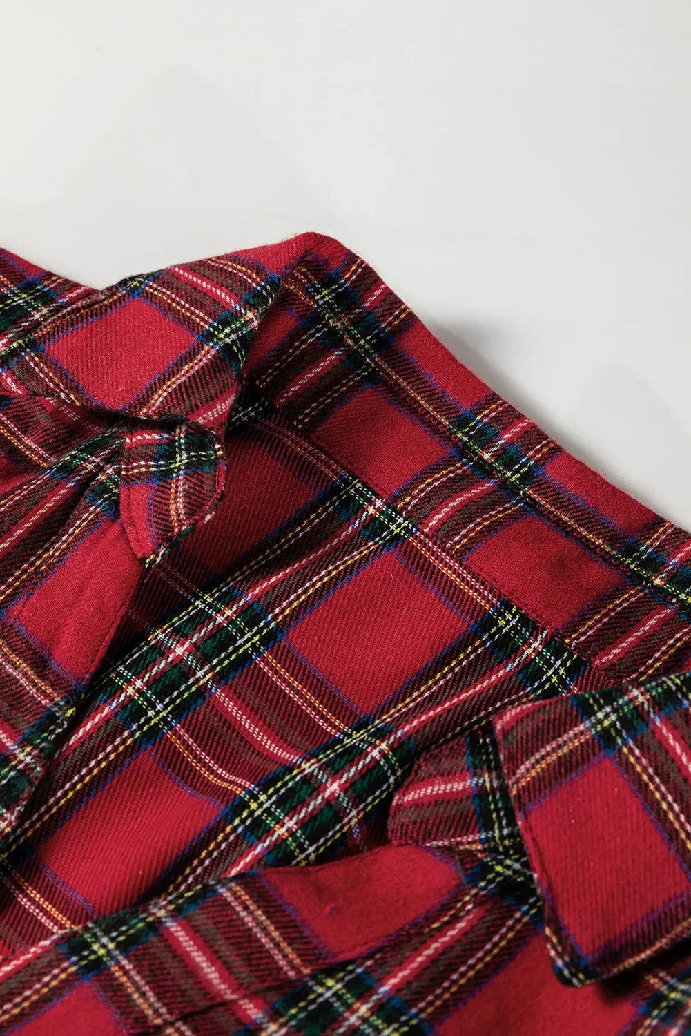 Red plaid patterned women's mini dress with a shirt collar, long sleeves, half-button front, and a ruffle hem.
