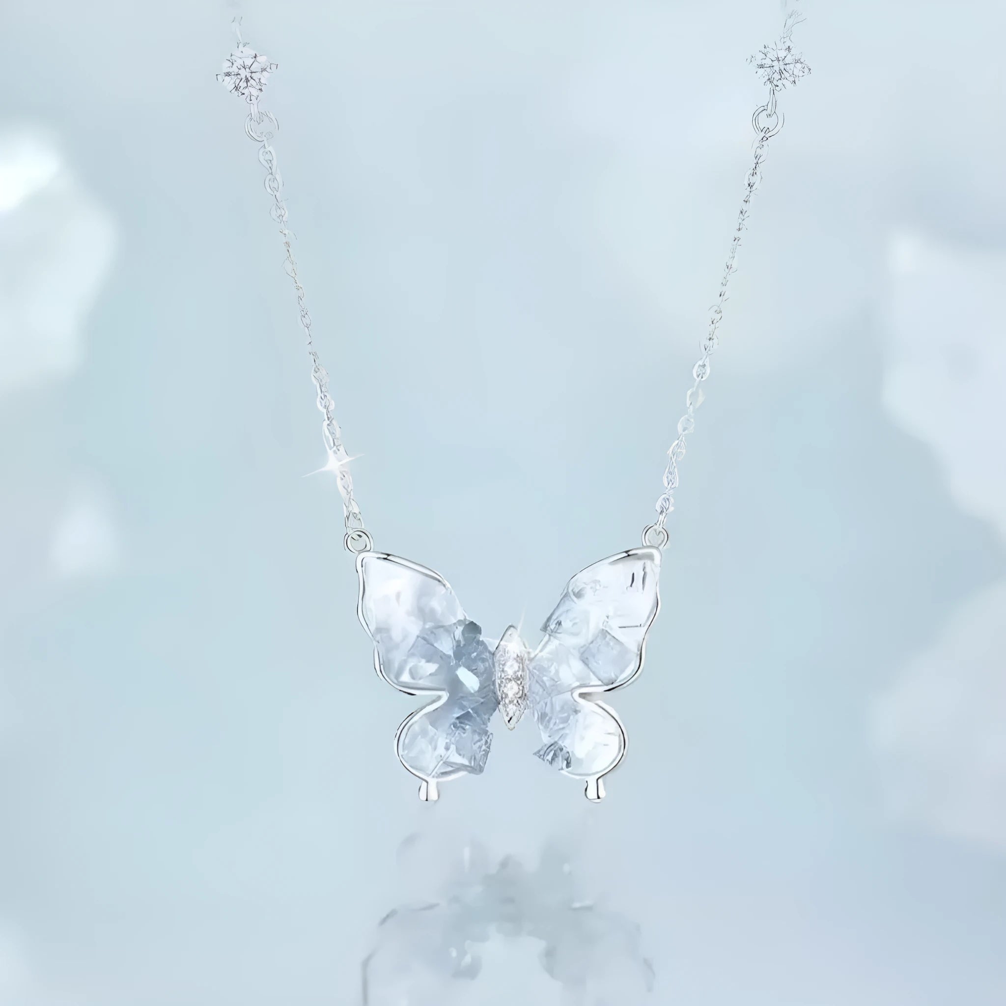 Close-up of a silver necklace with a detailed butterfly pendant on an O-ring chain.
