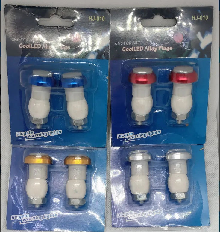 A pair of anodised aluminium bicycle handlebar end lights in a choice of colours, showing the red LED and white rubber switch.