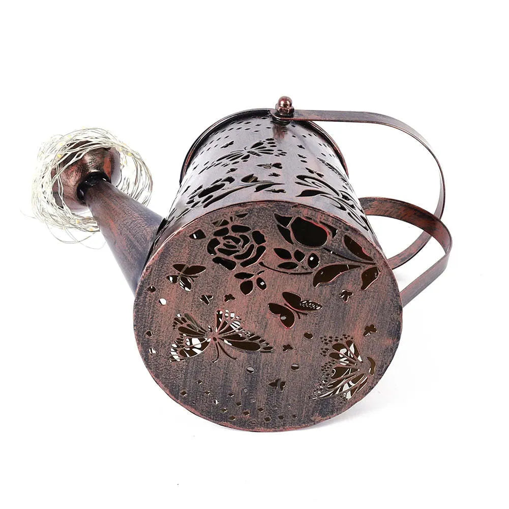 Iron solar garden lamp with a tapered butterfly silhouette emitting warm white light.