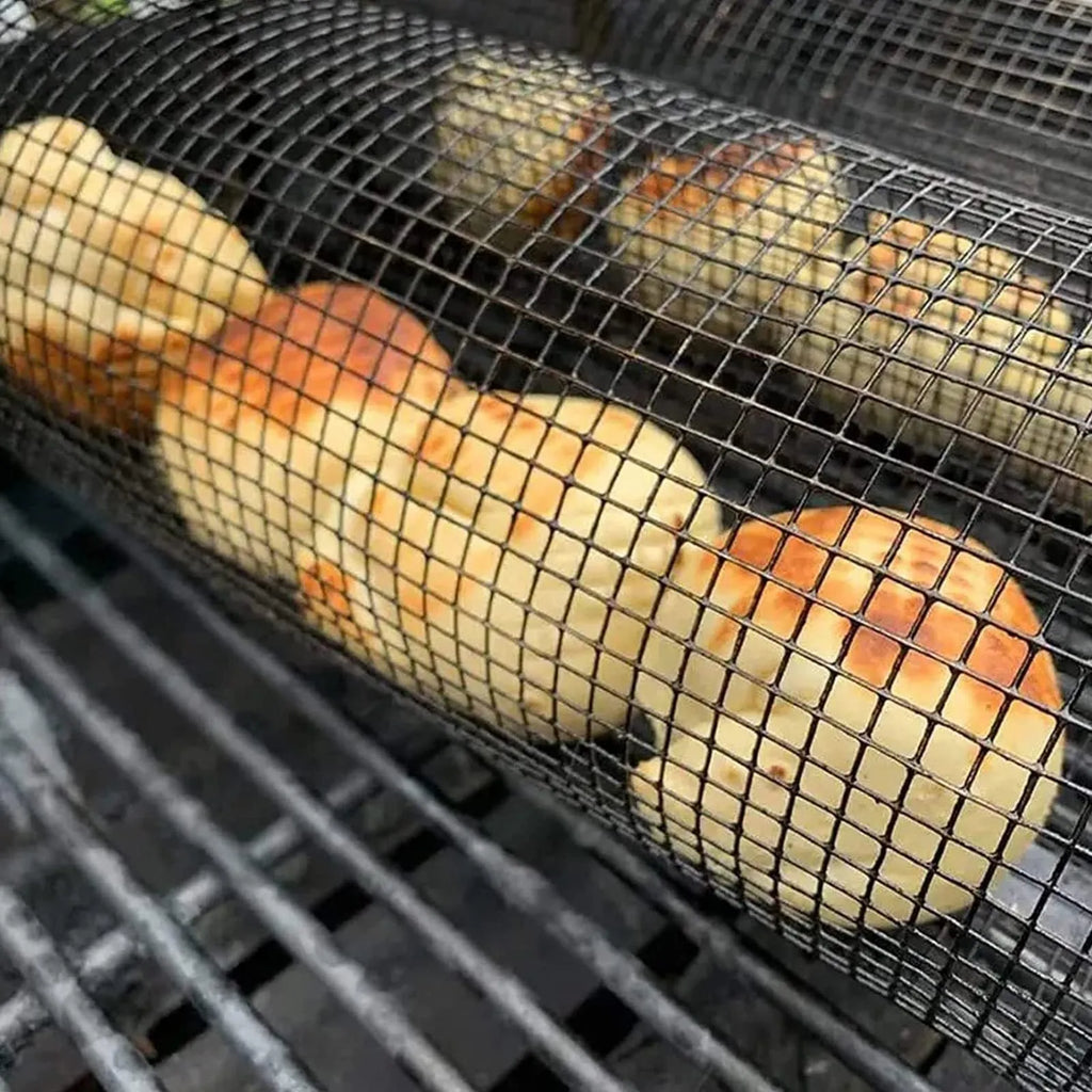 Round silver metal rolling barbecue basket with wire mesh and a hook, shown with vegetables inside on a grill.
