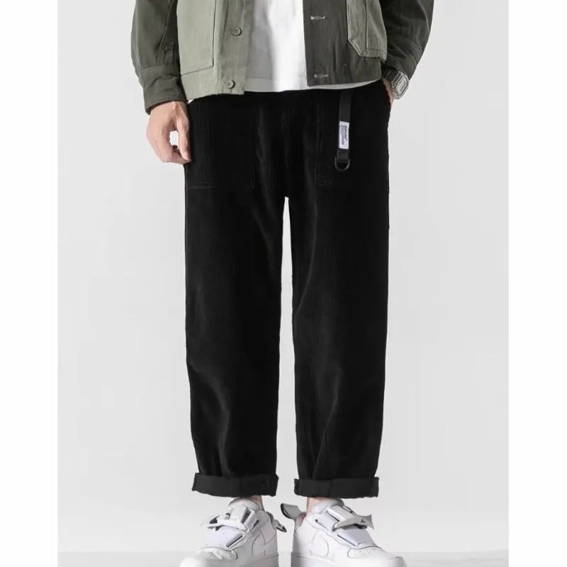 Man wearing loose straight-leg tapered trousers in dark grey, showing the full length and relaxed fit.