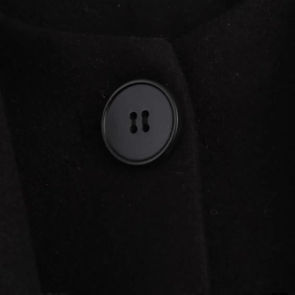 A woman wearing a longline black polyester coat with a detachable faux fur collar.