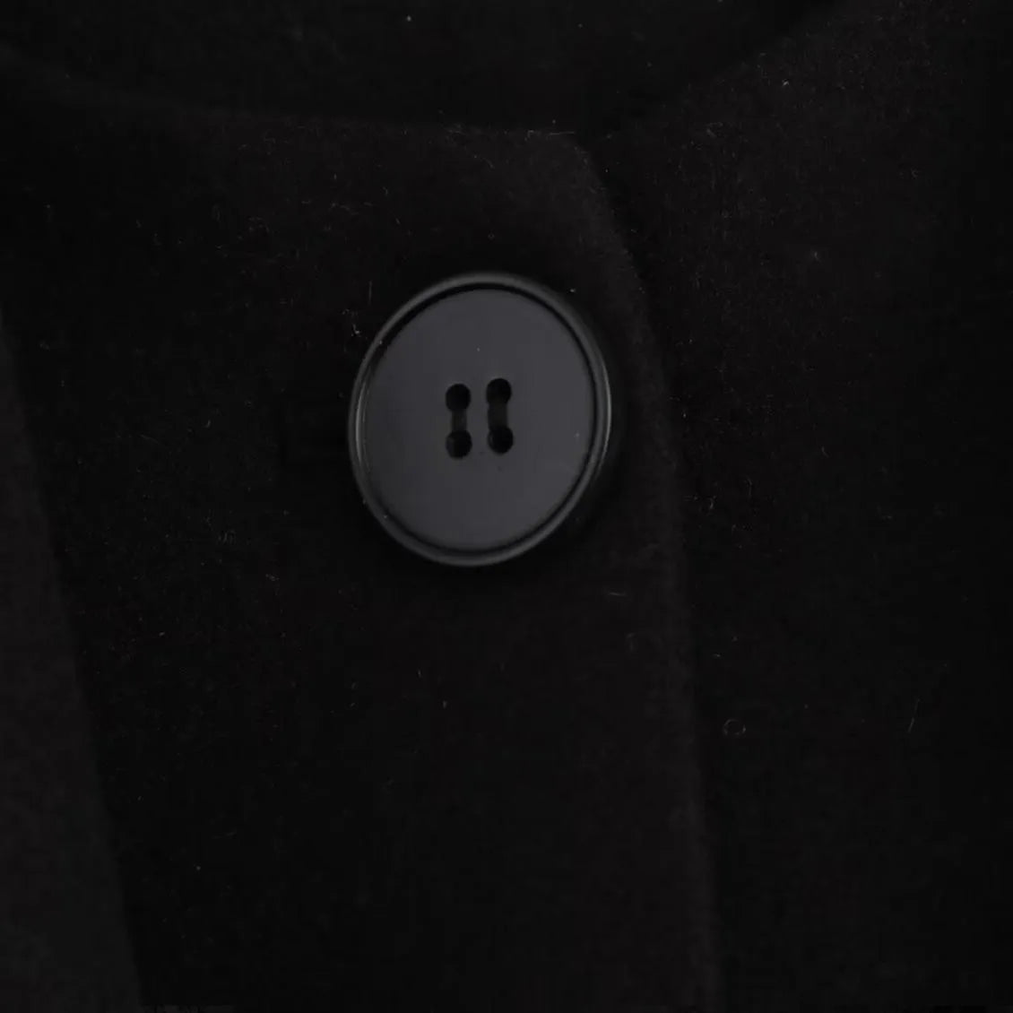 A woman wearing a longline black polyester coat with a detachable faux fur collar.