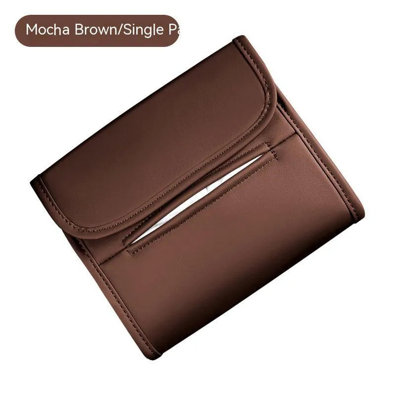 Brown leather car tissue box with elastic strap hanging on a car seat back.