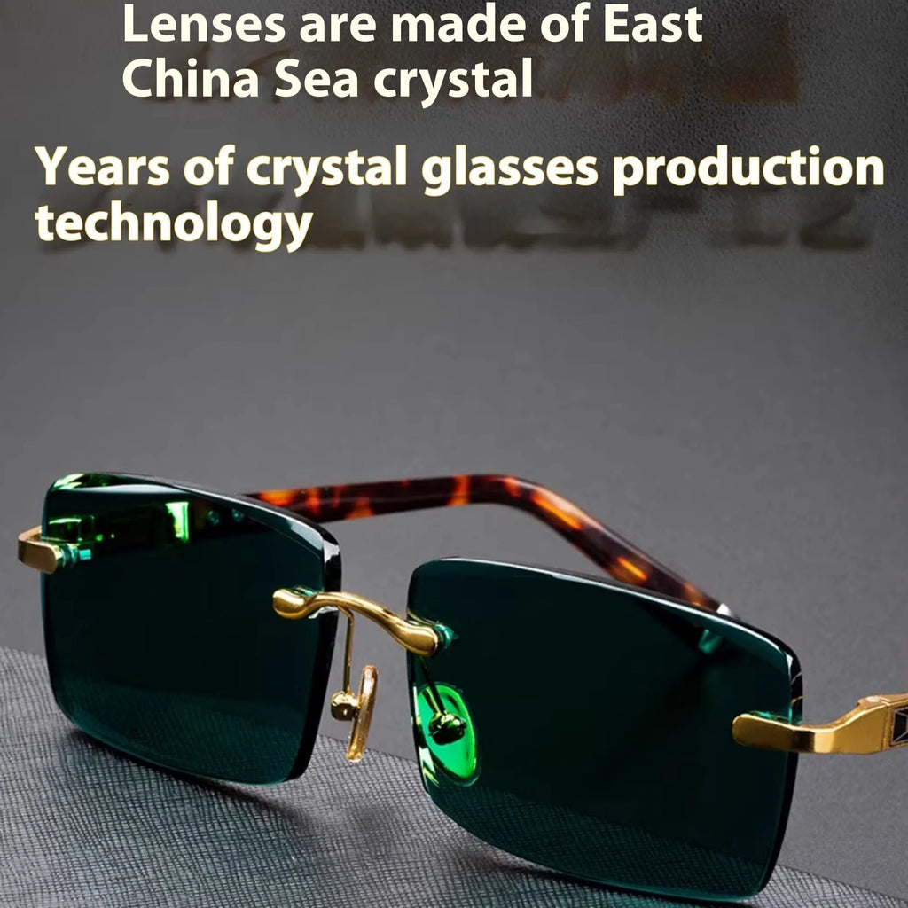 A pair of dark green frameless crystal sunglasses with a hard case and a lens cloth on a plain background.