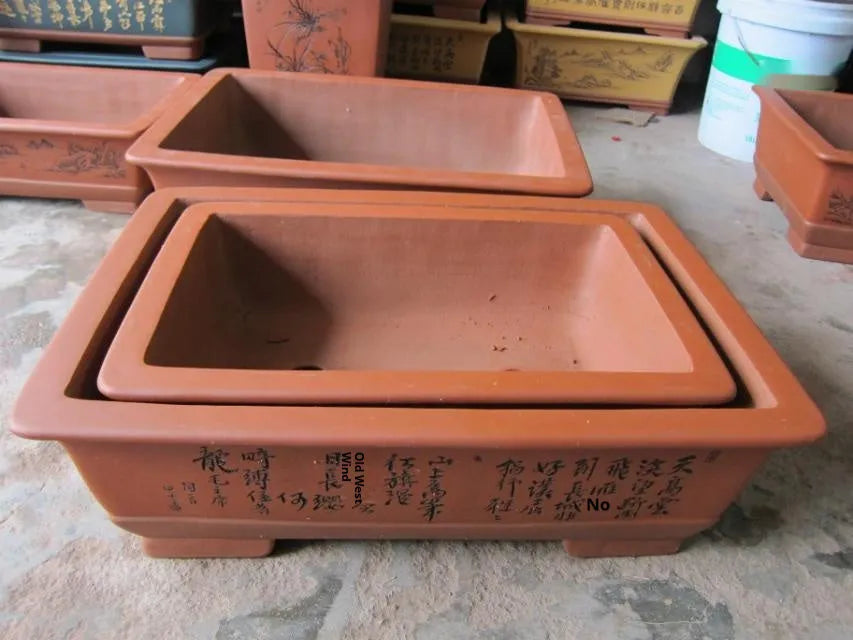 Two Yixing purple clay rectangular flower pots in different sizes on a wooden surface