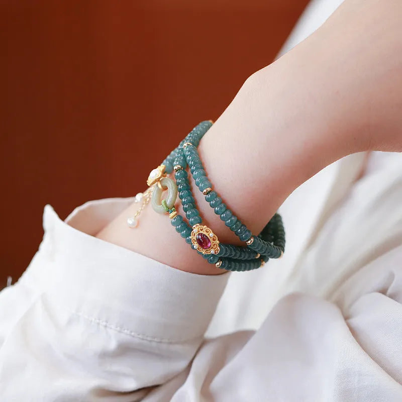 Close-up of a blue water jade and abacus bead bracelet with tourmaline rings and freshwater pearls.