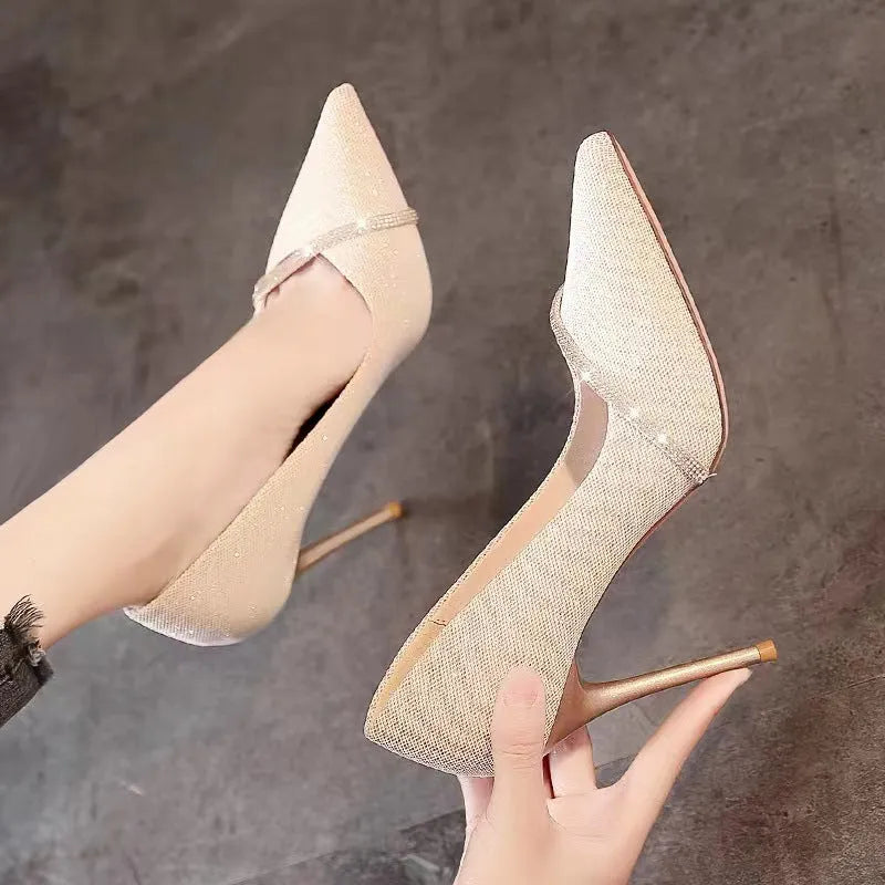 Gold women's stiletto pointed toe high heels on a plain background.