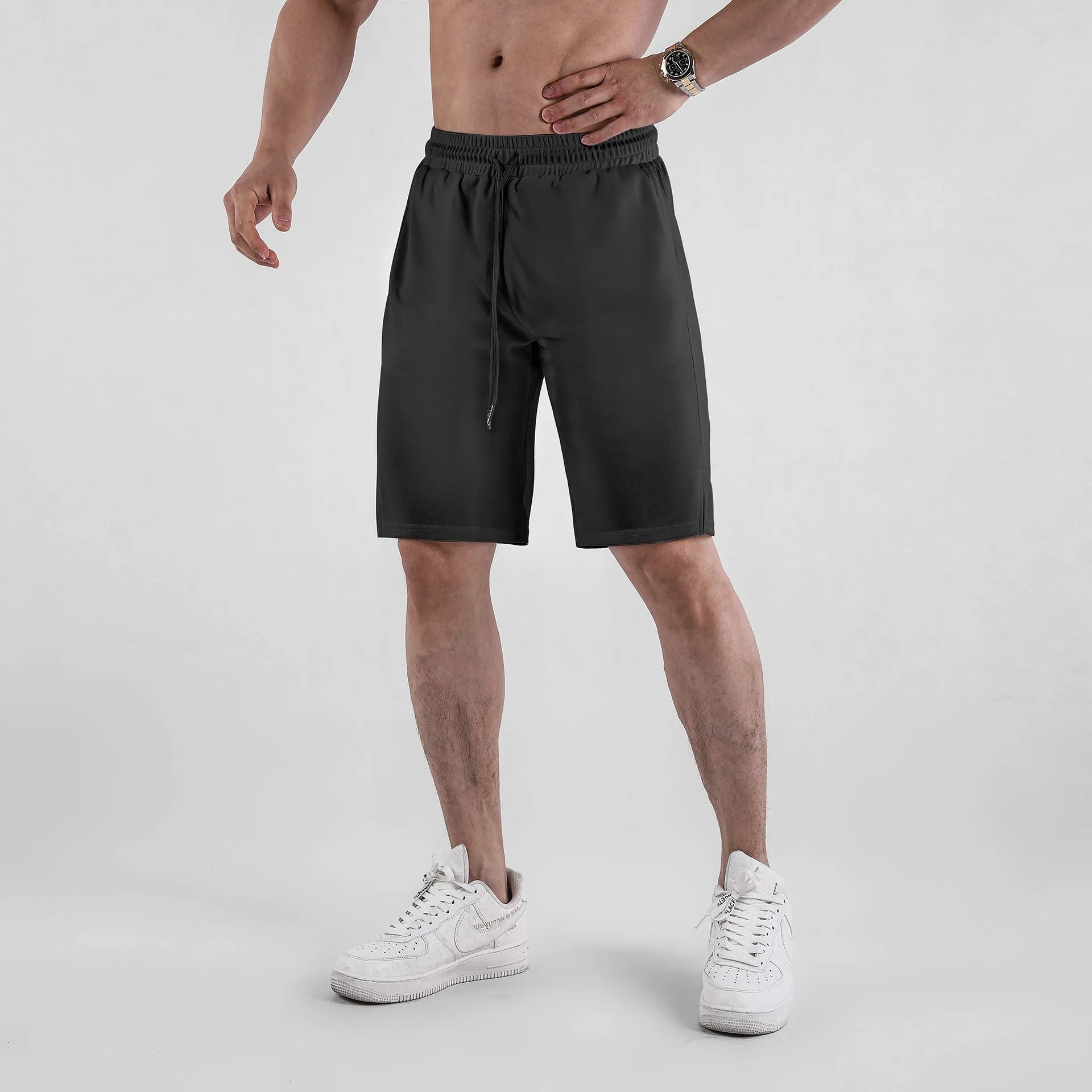Man wearing black loose-fit mesh capri shorts with an elastic waist for sports.