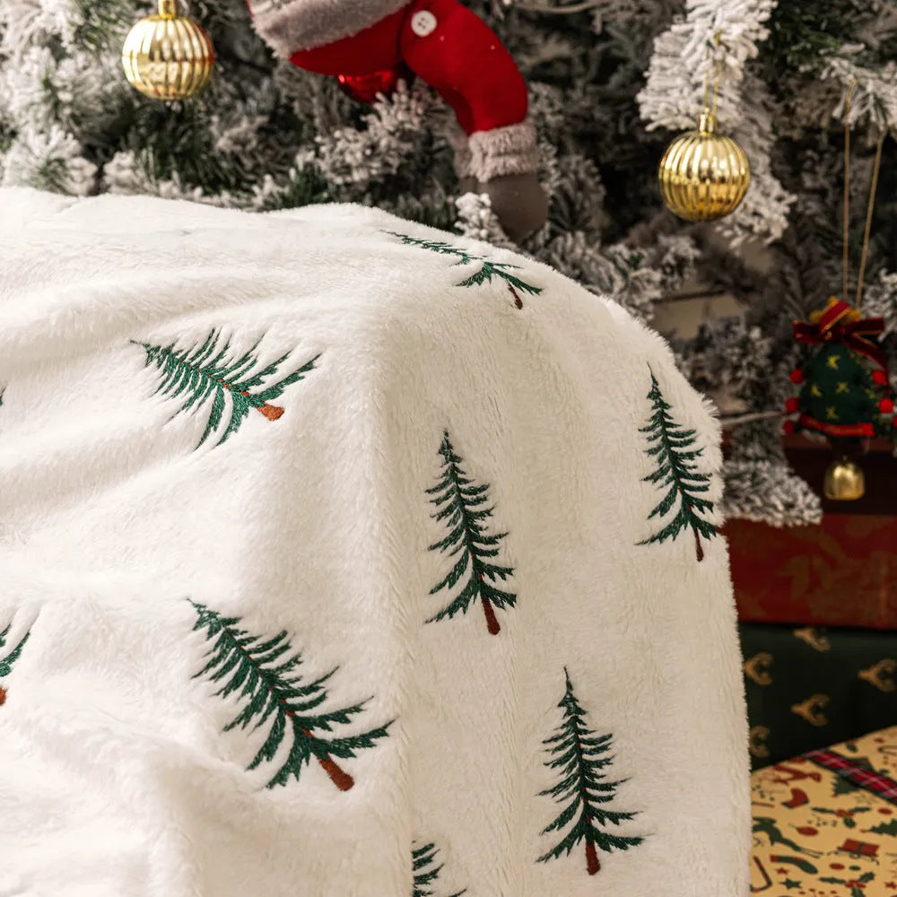 White Christmas plush sofa blanket with embroidered tree motif on a living room sofa