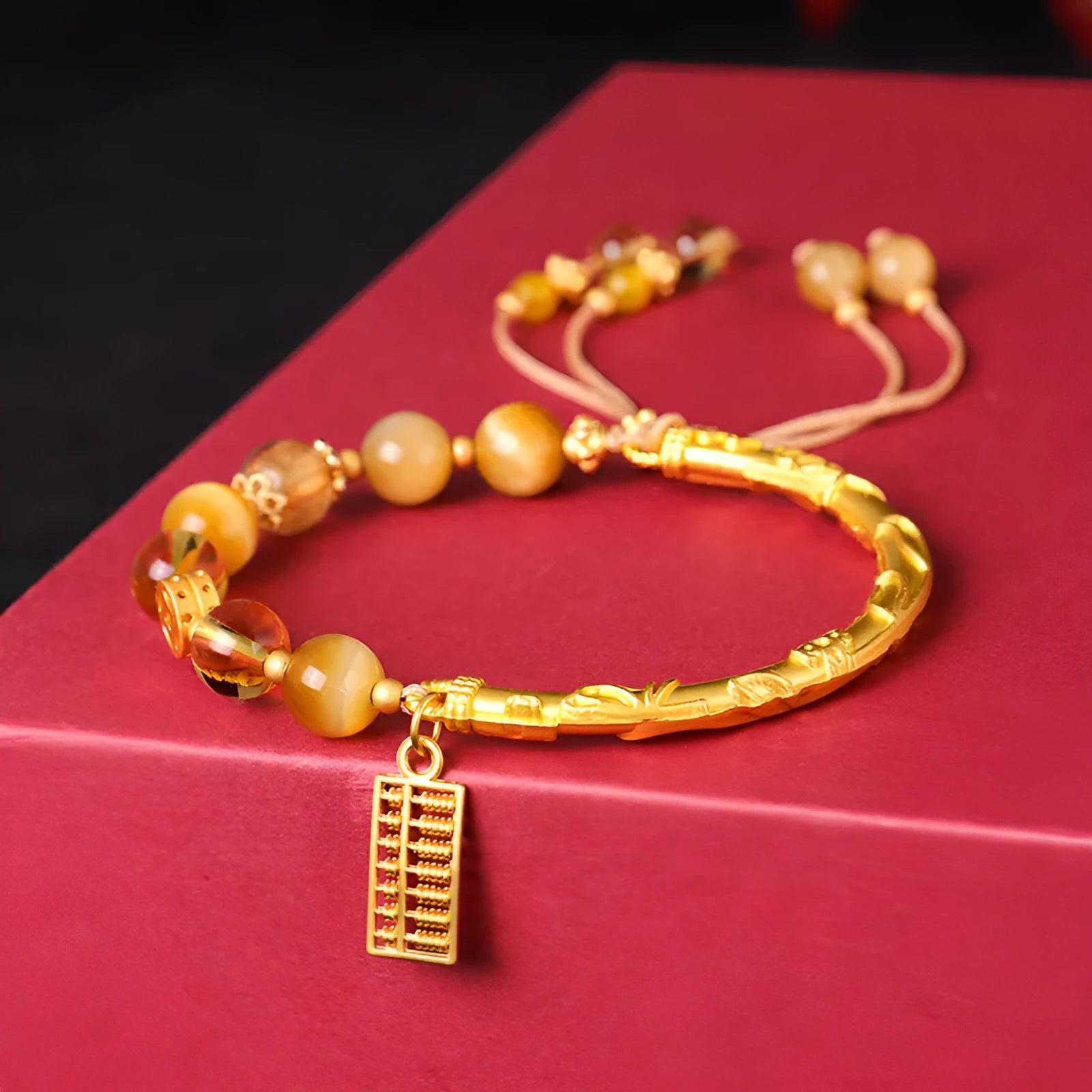 Close-up of handmade abacus bracelet with tigereye, citrine, and yellow tower crystal beads in a diamond shape on a wrist.