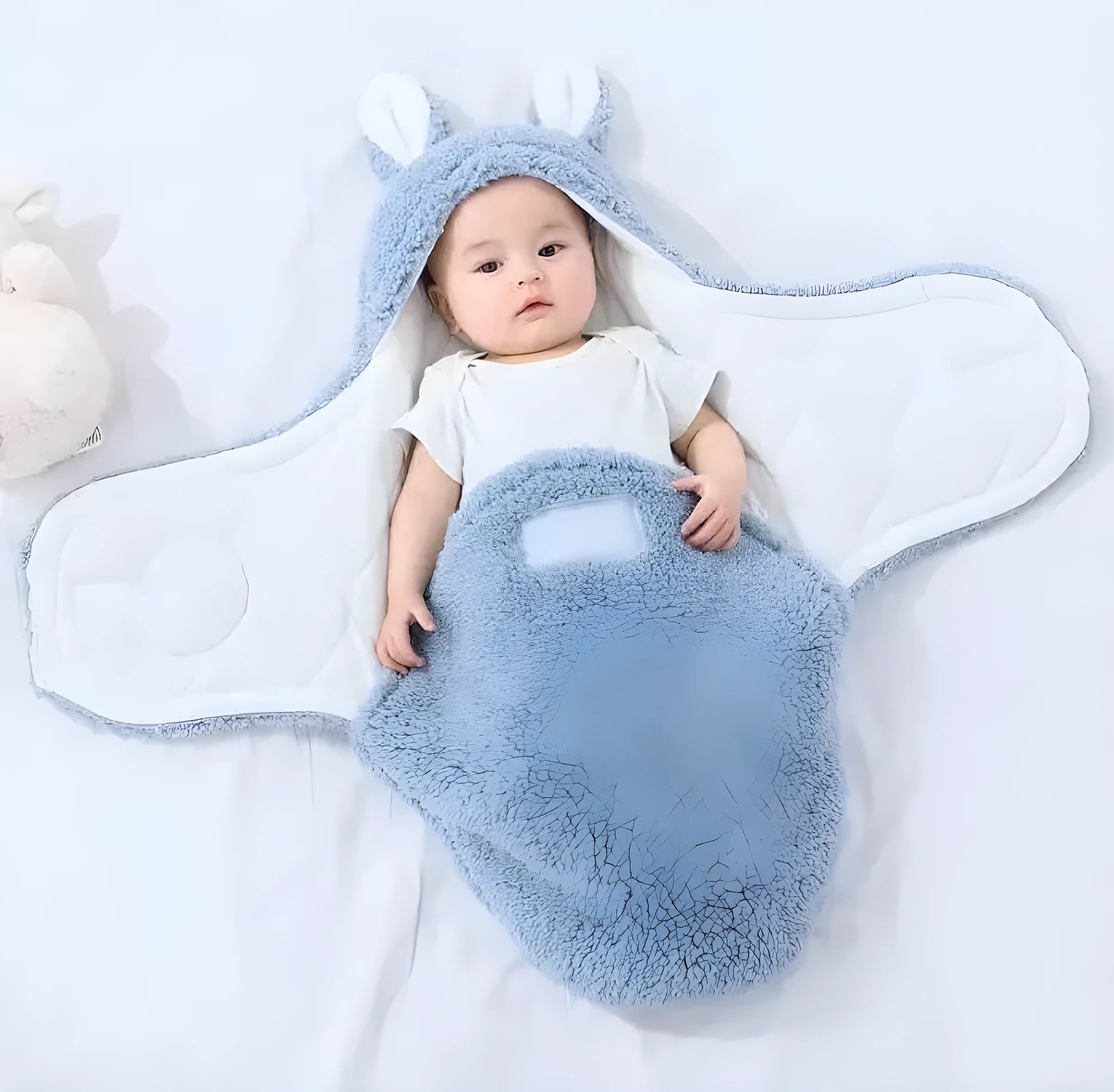 A baby wearing a soft grey fleece sleeping bag with hook-and-loop shoulder straps.