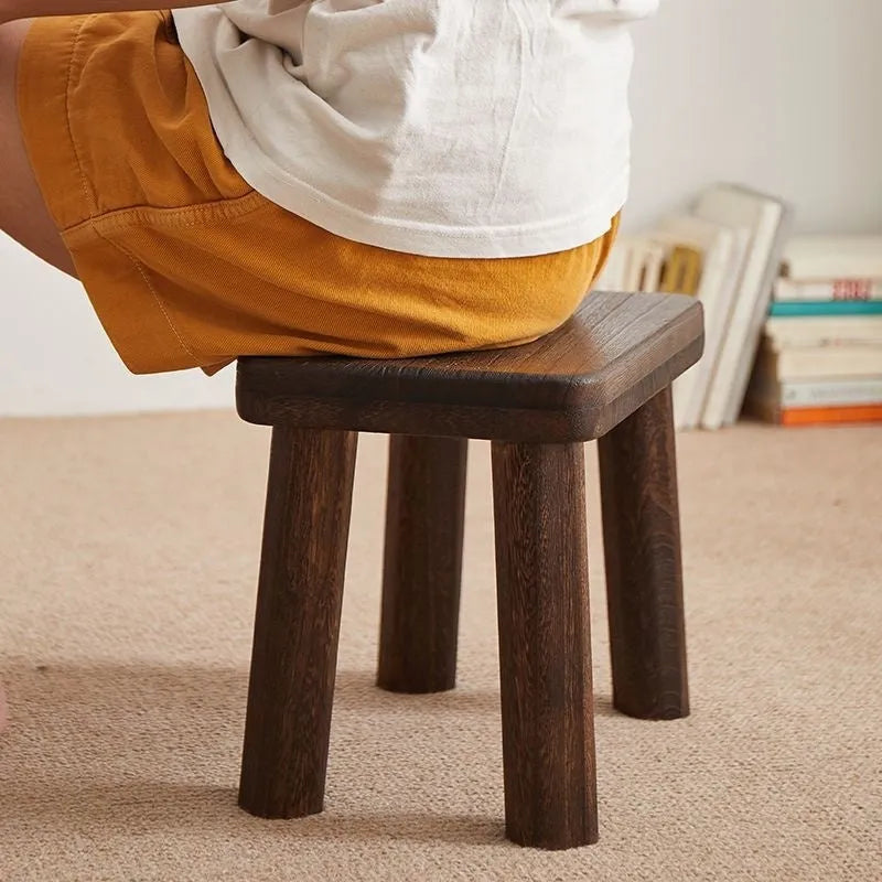 Solid wood distressed finish shoe changing stool on a wooden floor