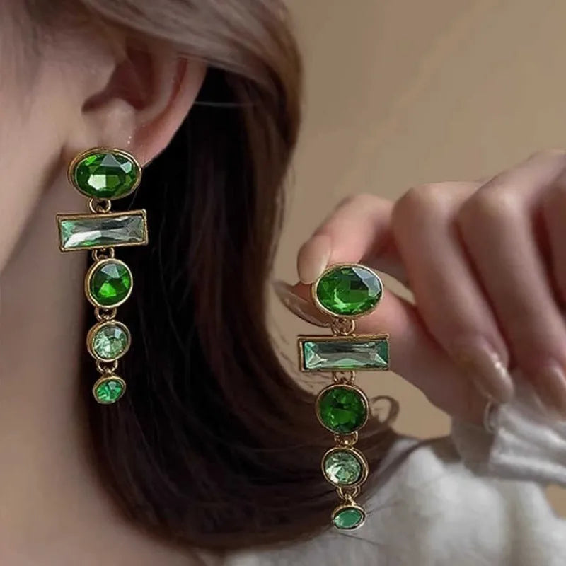 A pair of green gradient geometric drop earrings with inlaid zircon stones and a dangling tassel detail.