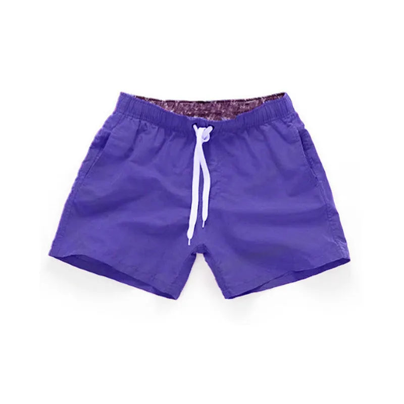 Men's straight-leg polyester surf shorts on a beach, available in multiple colours including fluorescent yellow and black.