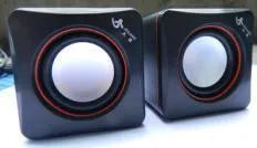 Black square USB-powered 2.0 desktop computer speaker on a desk.