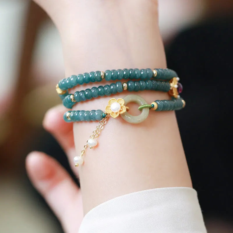 Close-up of a blue water jade and abacus bead bracelet with tourmaline rings and freshwater pearls.
