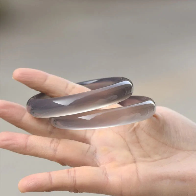 Close-up of a dark grey Brazilian agate bracelet showing circle and line patterns on the stone.