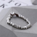 Handmade silver bracelet with an irregular square design and wooden details on an elasticated band.