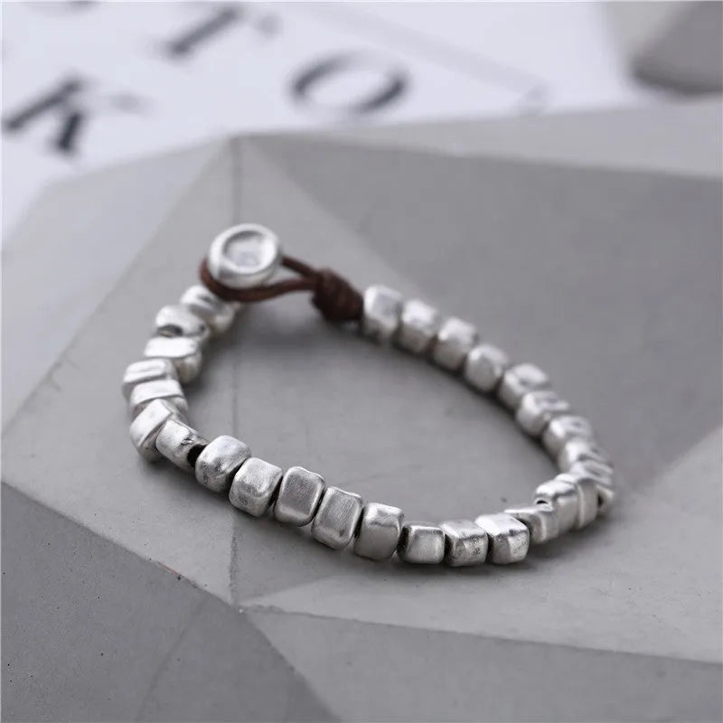 Handmade silver bracelet with an irregular square design and wooden details on an elasticated band.